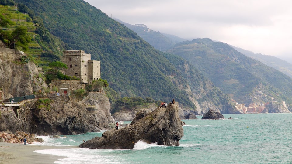 A coastal landscape with a historic stone building on a cliff, rocky outcrops, and a view of the sea.