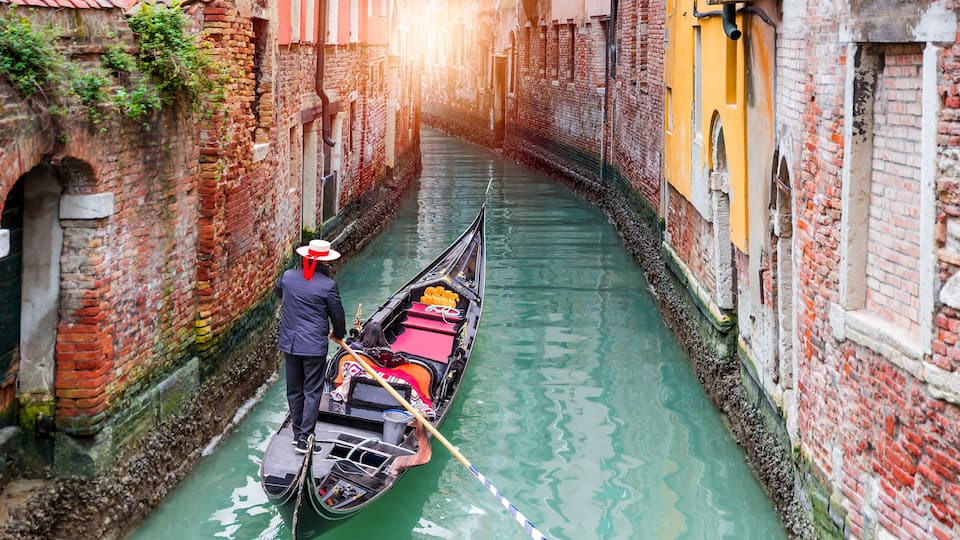 A narrow canal with a gondola and a gondolier in a historic European city.