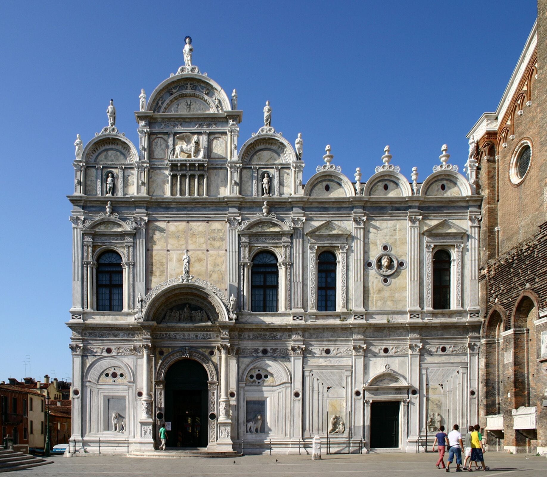 Un edificio histórico imponente con columnas ornamentadas, un amplio arco central y estatuas en el techo.