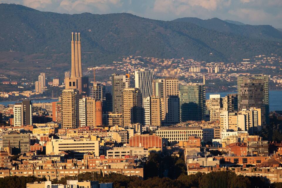 A cityscape with a prominent tower and a body of water in the background.