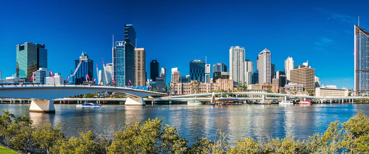 A city skyline with modern skyscrapers and a river with a bridge.