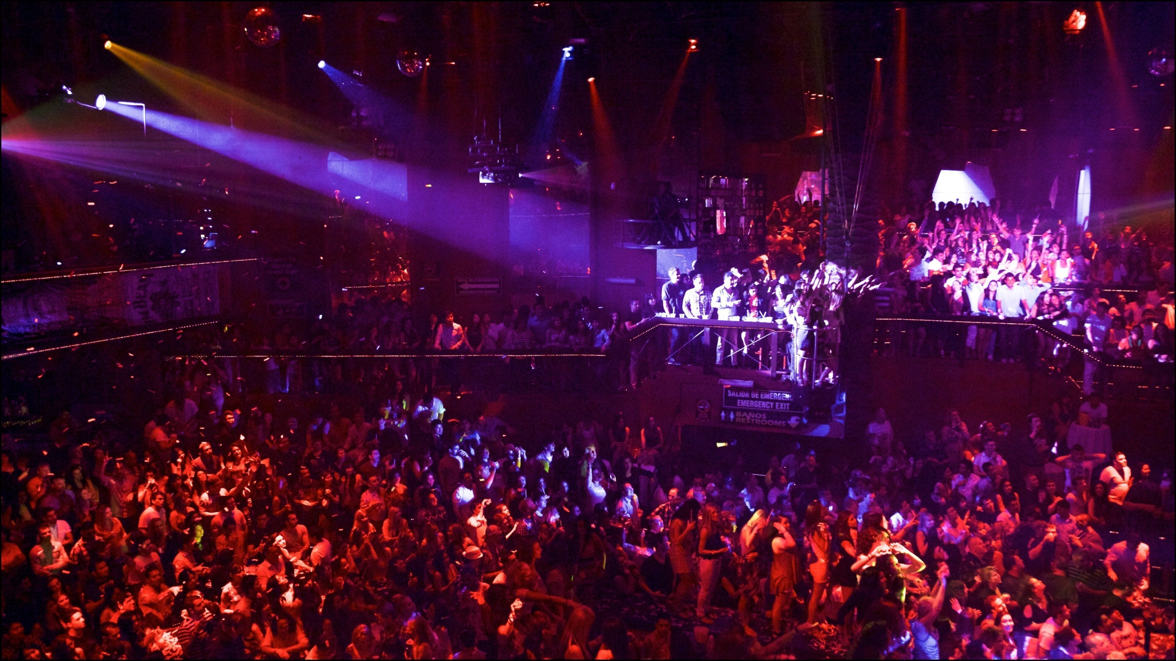 A crowded nightclub with a stage and DJ booth.