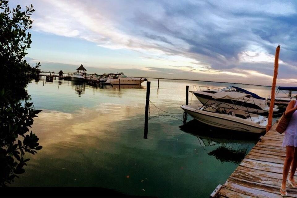 A wooden pier extending into calm waters with boats docked at the end.