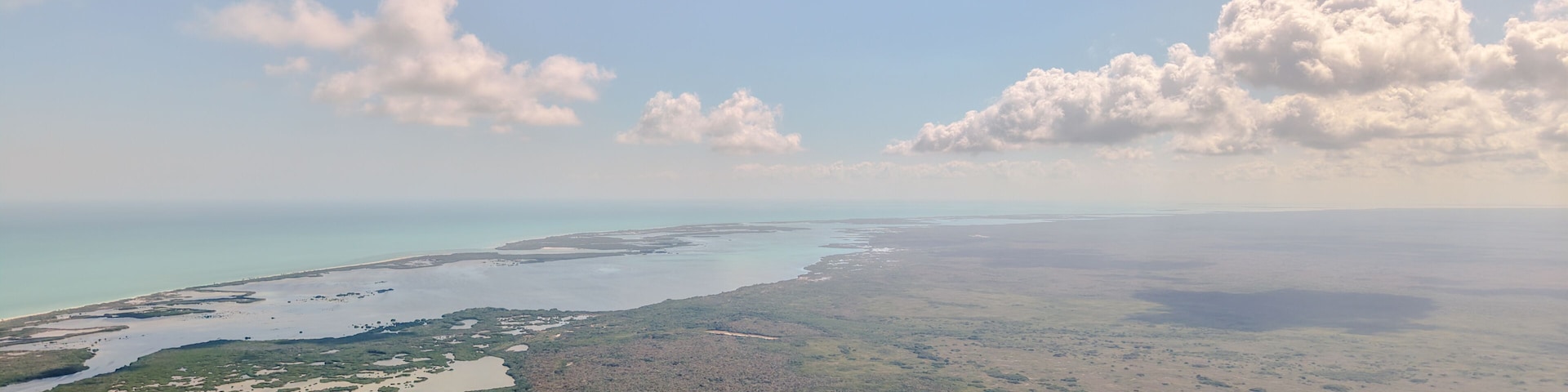Vista aérea de uma paisagem costeira com corpos d'água e vegetação verde.