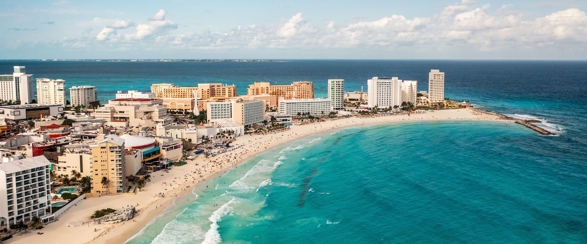 A coastal cityscape with a beach, hotels, and a clear blue sea.