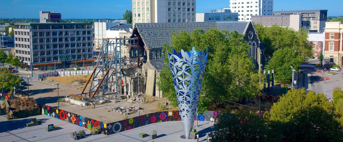 A cityscape with modern buildings, a construction site, and a distinctive blue sculpture.