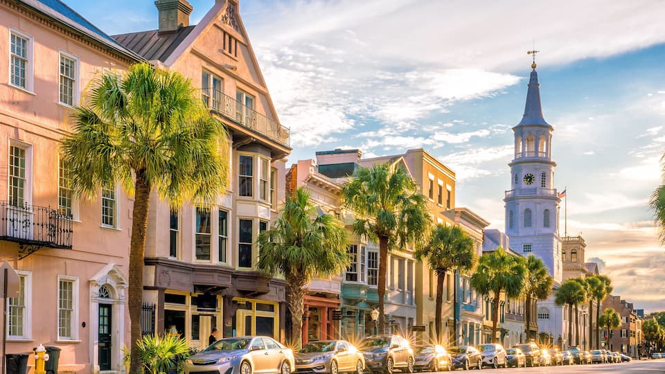 A historic street lined with palm trees and classic architecture, including a prominent clock tower.