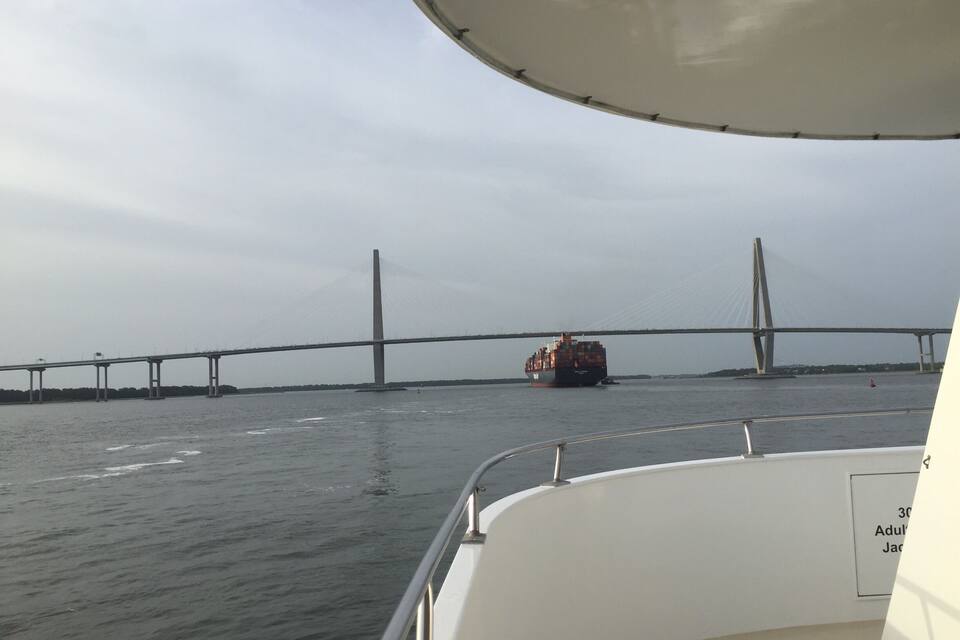 Um navio de carga num rio, com uma ponte ao fundo.