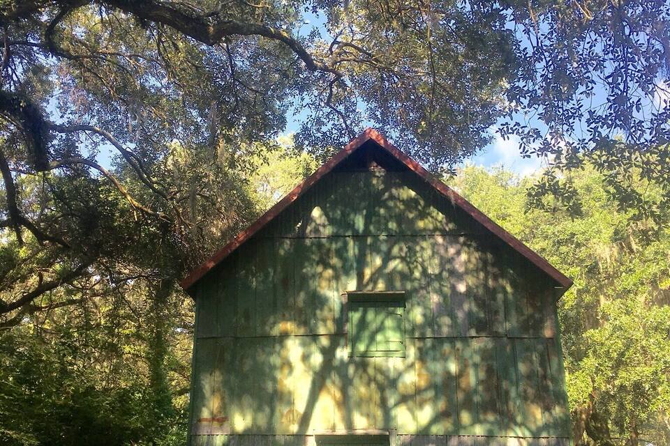 Un edificio de madera con techo rojo, rodeado de árboles y vegetación.