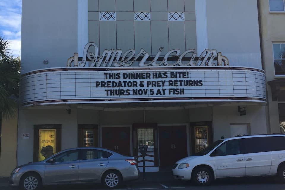 Ein Theatertheater mit einer Schrifttafel, auf der steht: 'Dieses Abendessen hat es in sich! PREDATOR & PREY kehrt am Donnerstag, den 5. November im FISH zurück.'