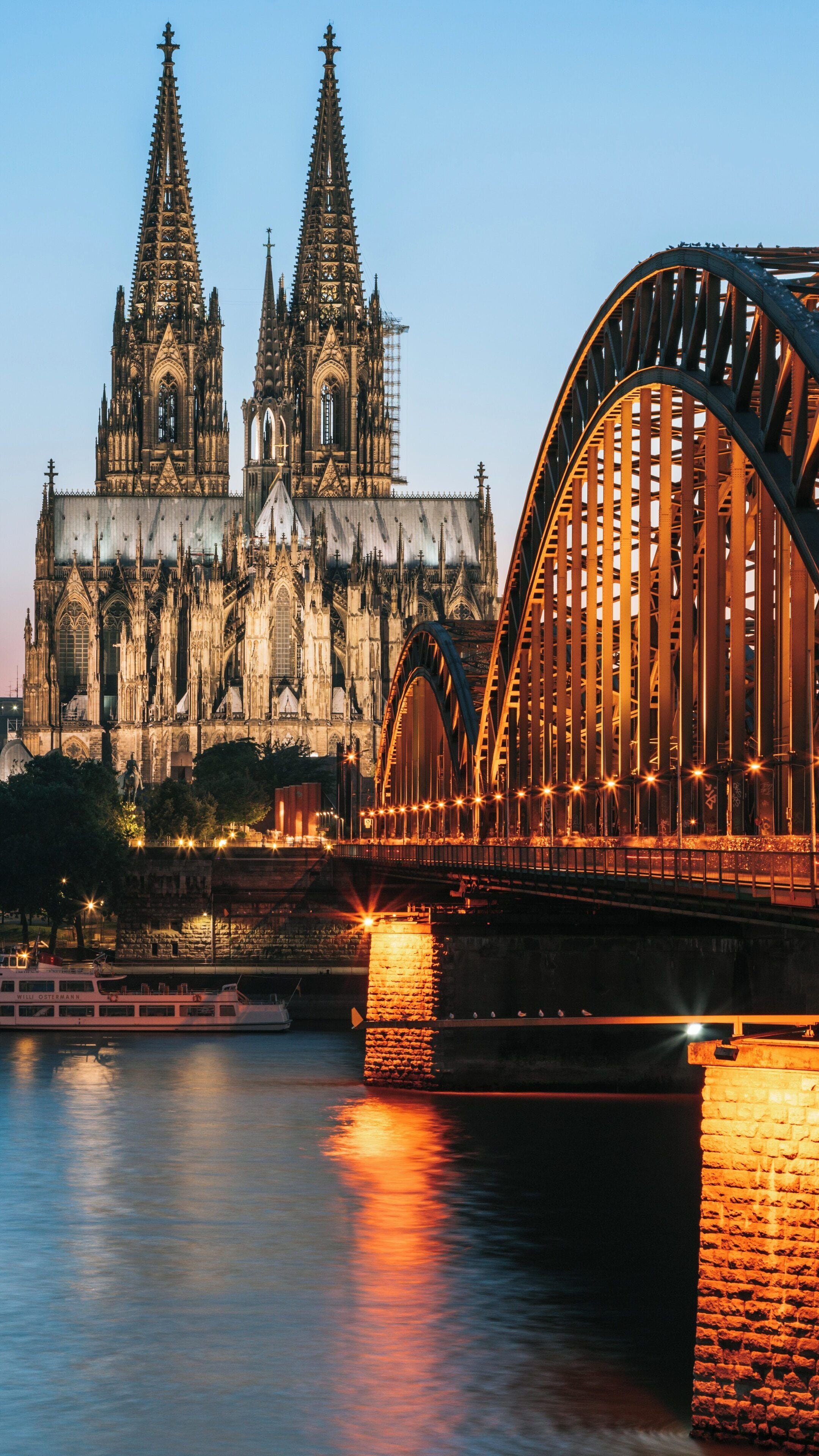 Hohenzollern Bridge illuminated at dusk with Cologne Cathedral in the background, North Rhine-Westphalia, Germany
