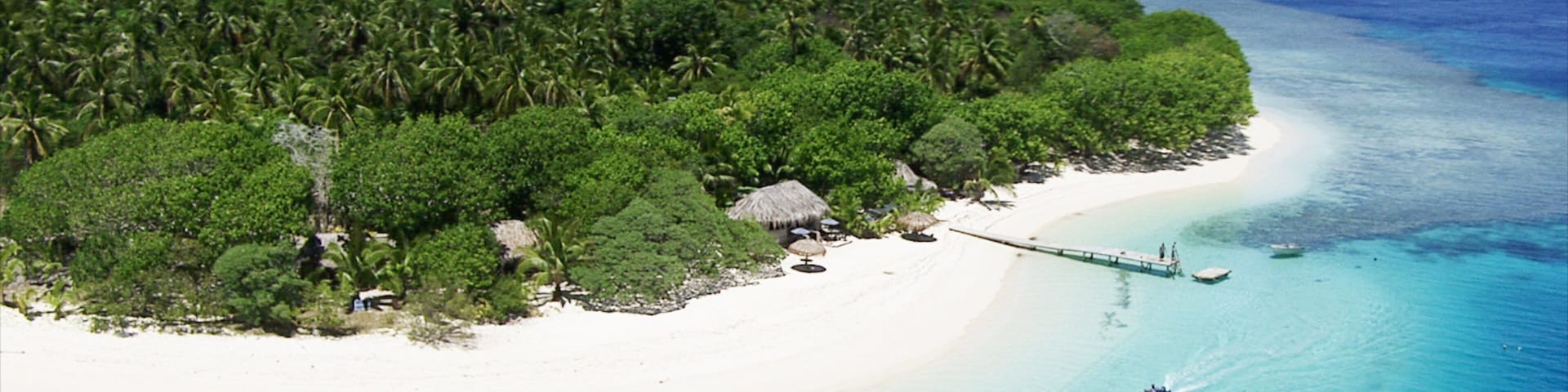 Una isla tropical con una playa de arena blanca, un bosque verde denso y aguas azules cristalinas.