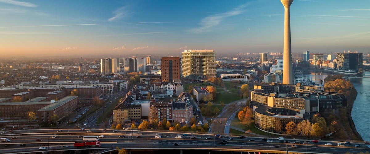 A cityscape with a prominent tower, a river, and a mix of modern and older buildings.