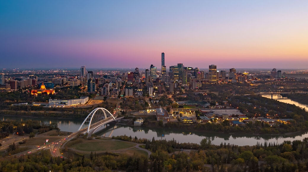Un horizonte urbano al anochecer con un puente destacado y un río.