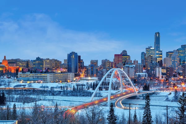 A city skyline with a prominent bridge and snow-covered landscape.