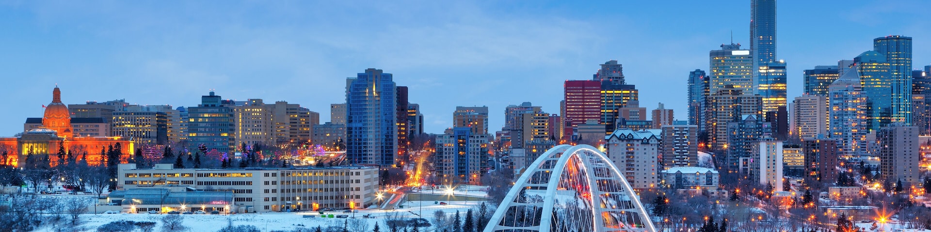 A city skyline with a prominent bridge and snow-covered landscape.