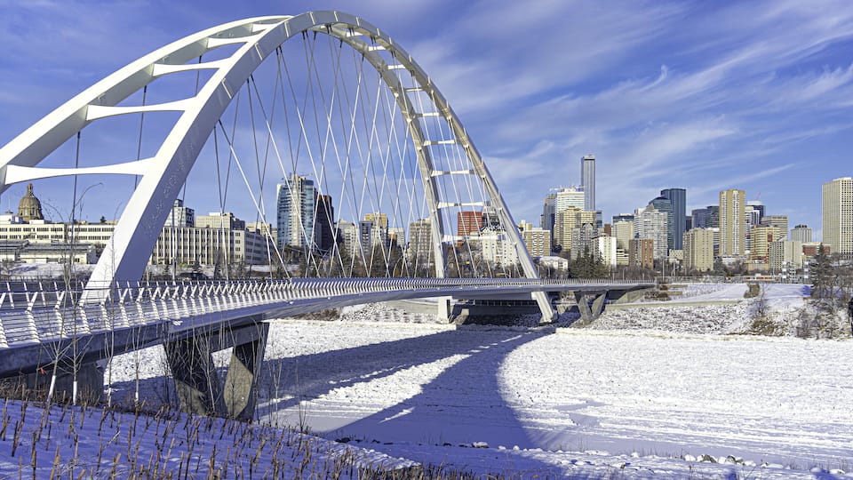 A snow-covered bridge with a city skyline in the background.