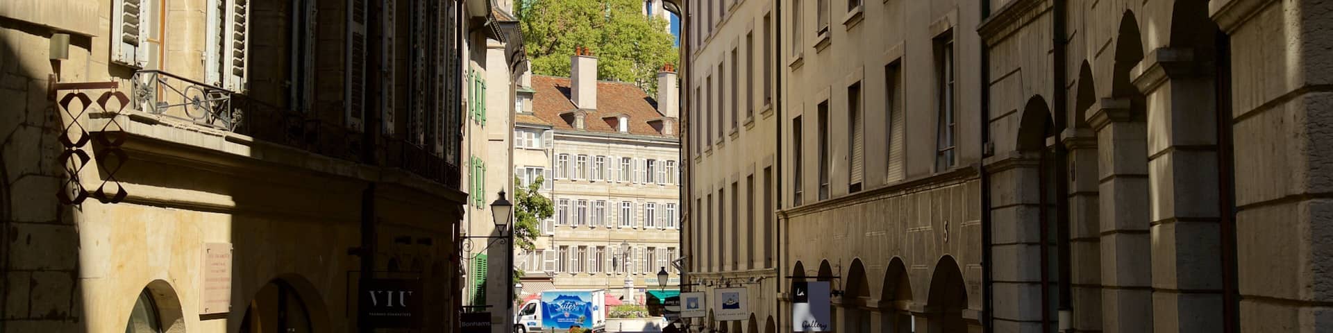 A narrow street with historic buildings, a church spire, and a blue truck.