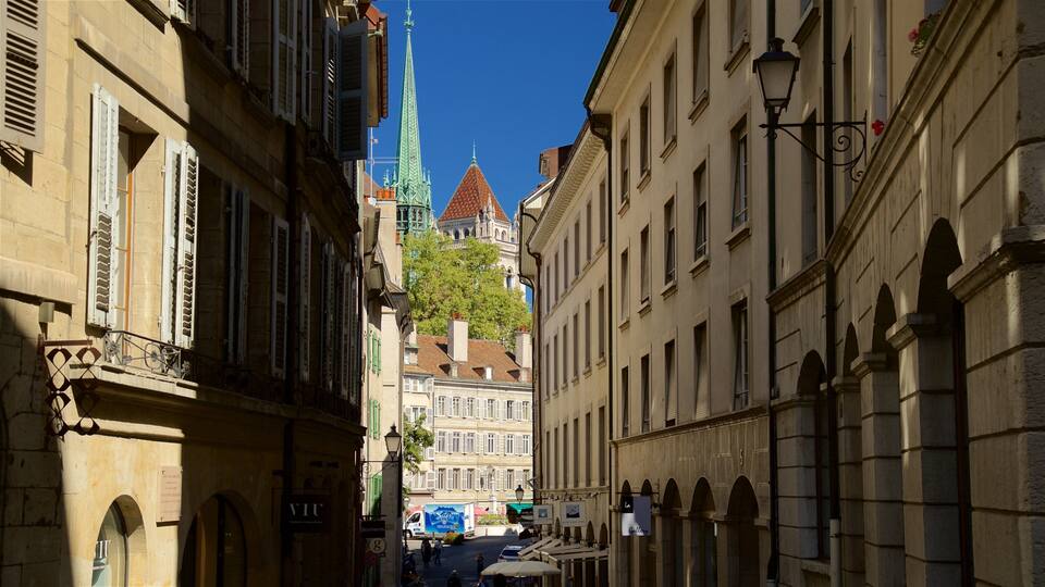 A narrow street with historic buildings, a church spire, and a blue truck.