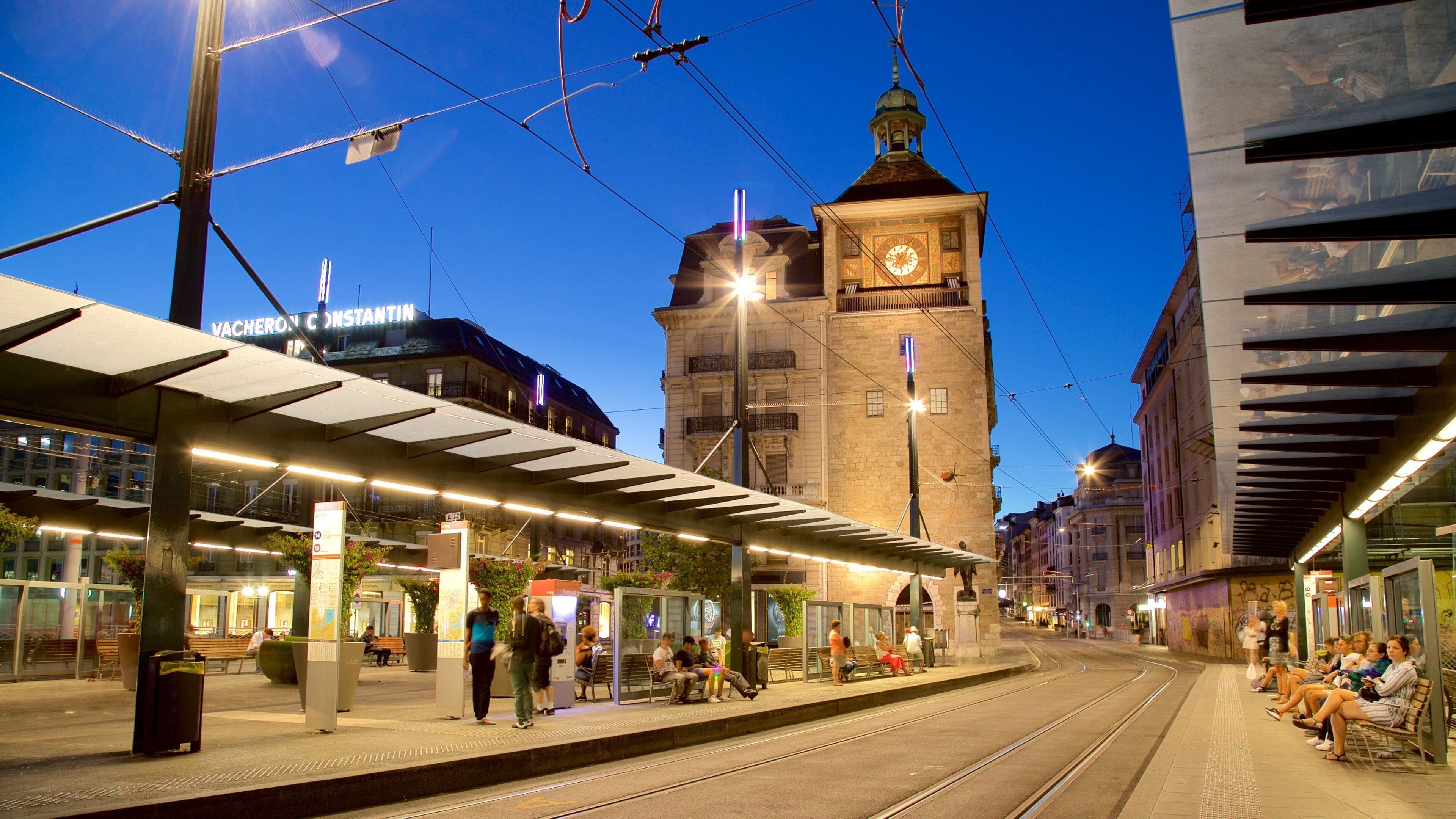 A tram station with a clock tower in the background.