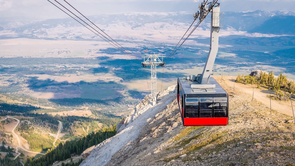 A cable car system in a mountainous area with a clear view of the valley below.
