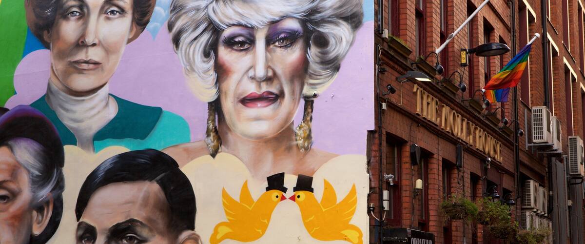 A mural with portraits and a building with a sign reading "THE KOLLEHOUSE".
