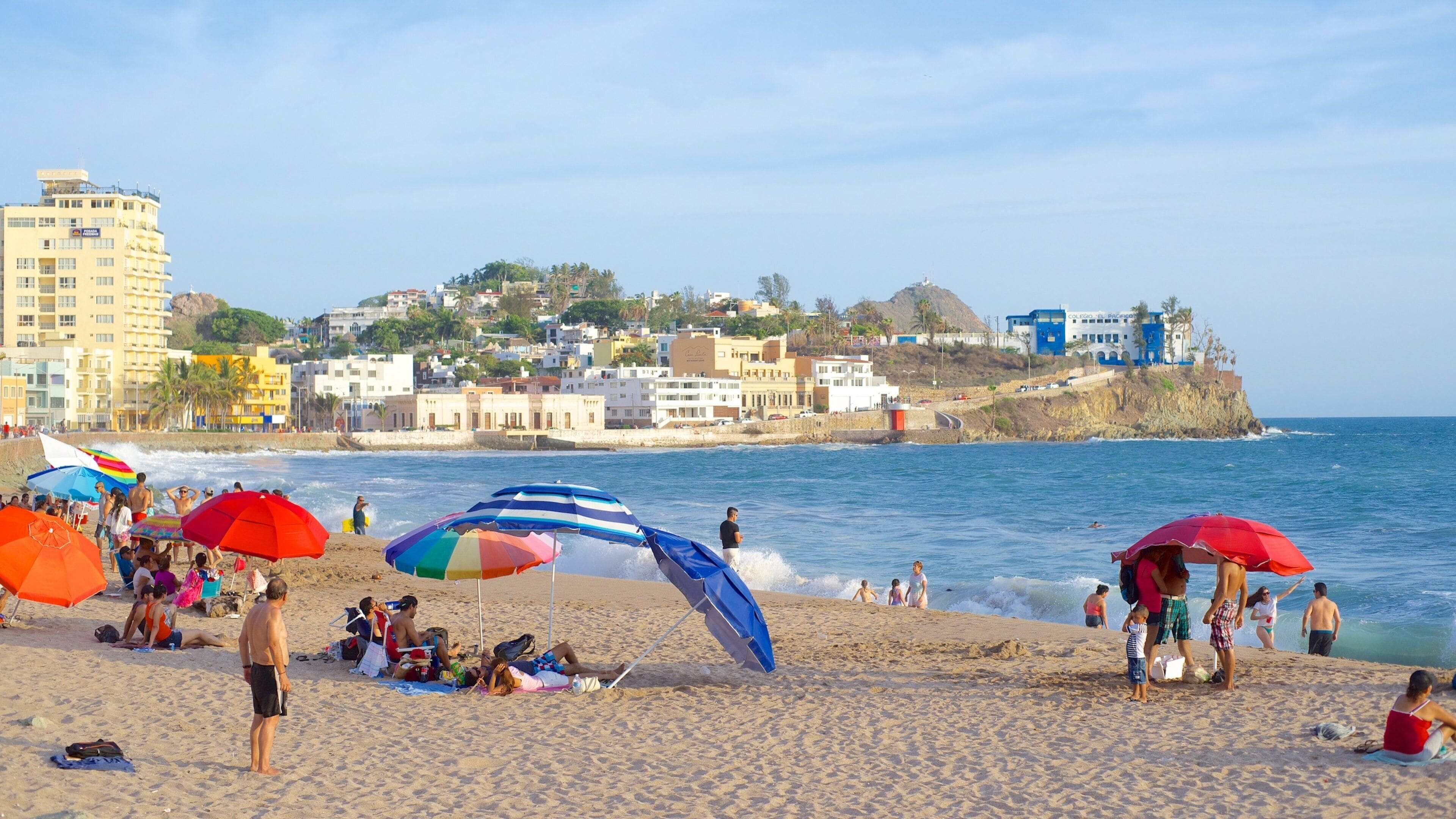 Mazatlán mostrando una playa de arena y una ciudad costera y también un gran grupo de personas