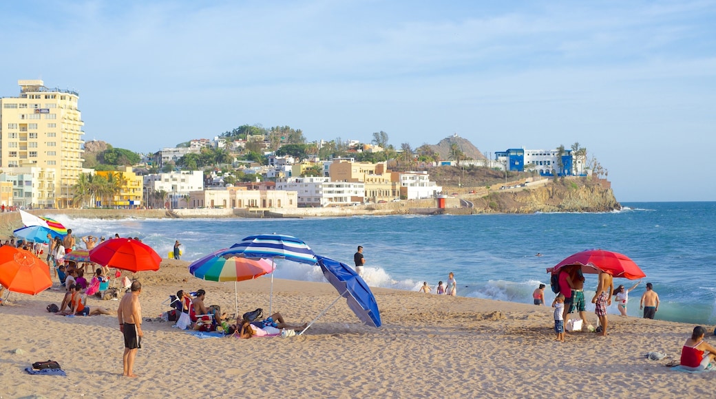 Mazatlán mostrando una playa de arena y una ciudad costera y también un gran grupo de personas