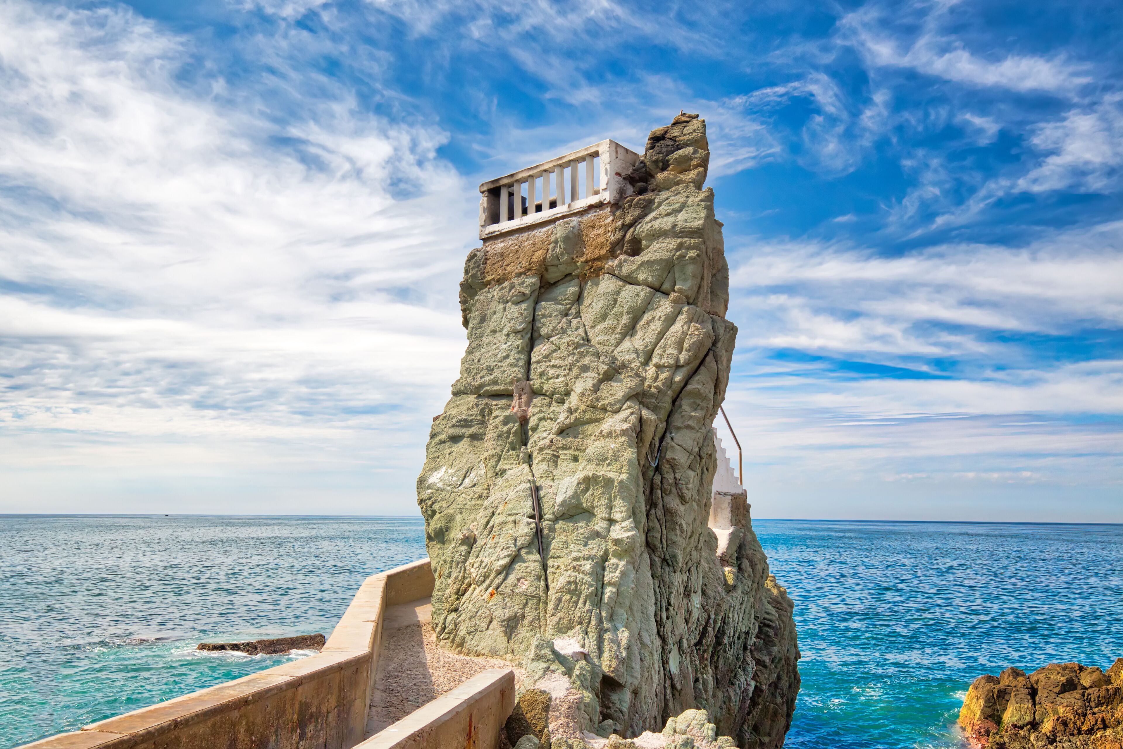 A rocky cliff with a small balcony overlooking the sea.