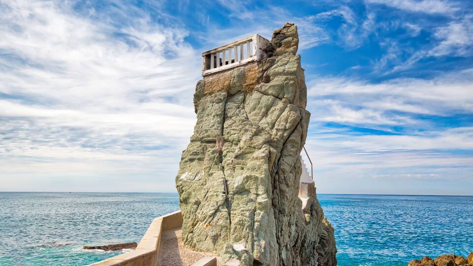 A rocky cliff with a small balcony overlooking the sea.