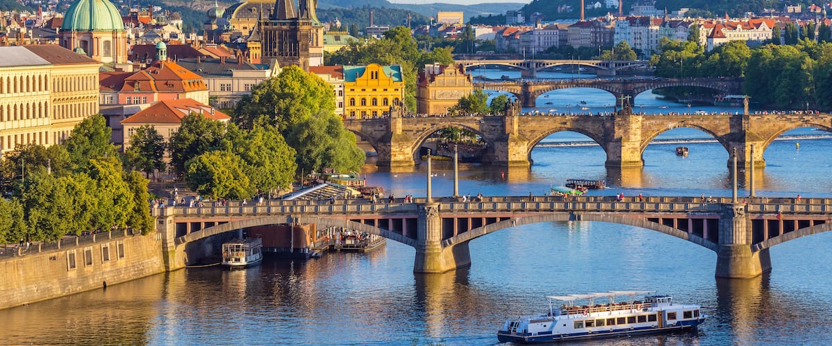 A river with a bridge, a boat, and historic buildings.