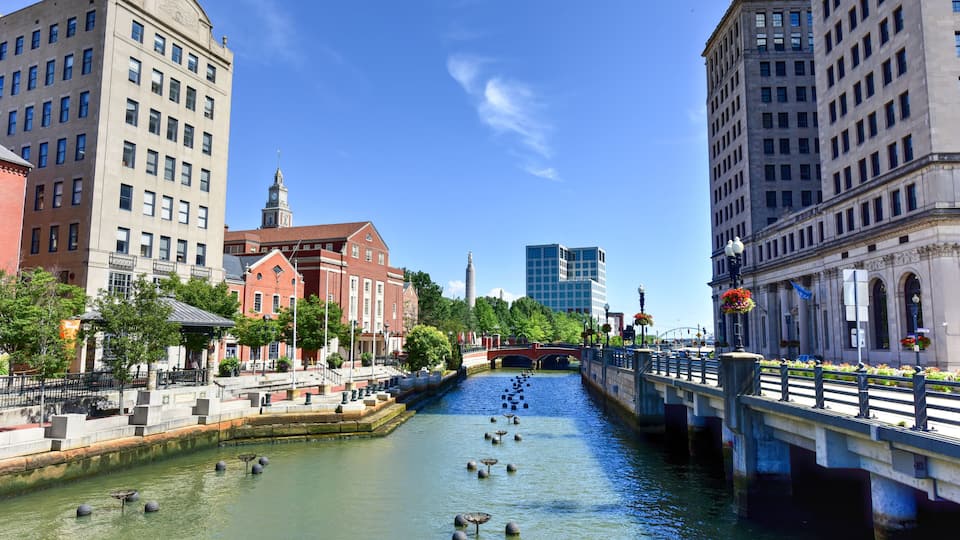 A river with fountains, a bridge, and buildings.