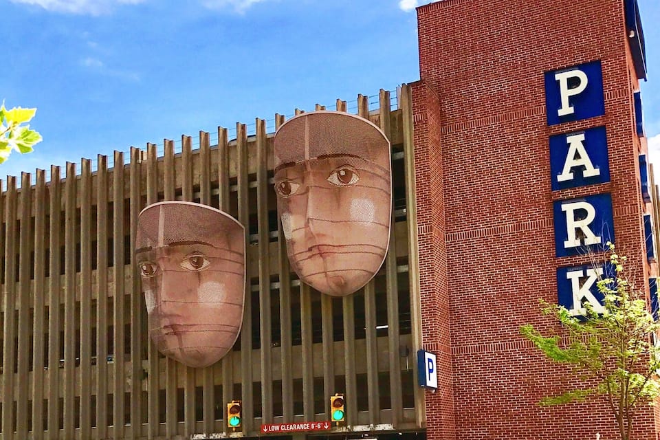 Een gebouw met een groot ‘PARK’ bord en twee grote gezichten op de gevel.
