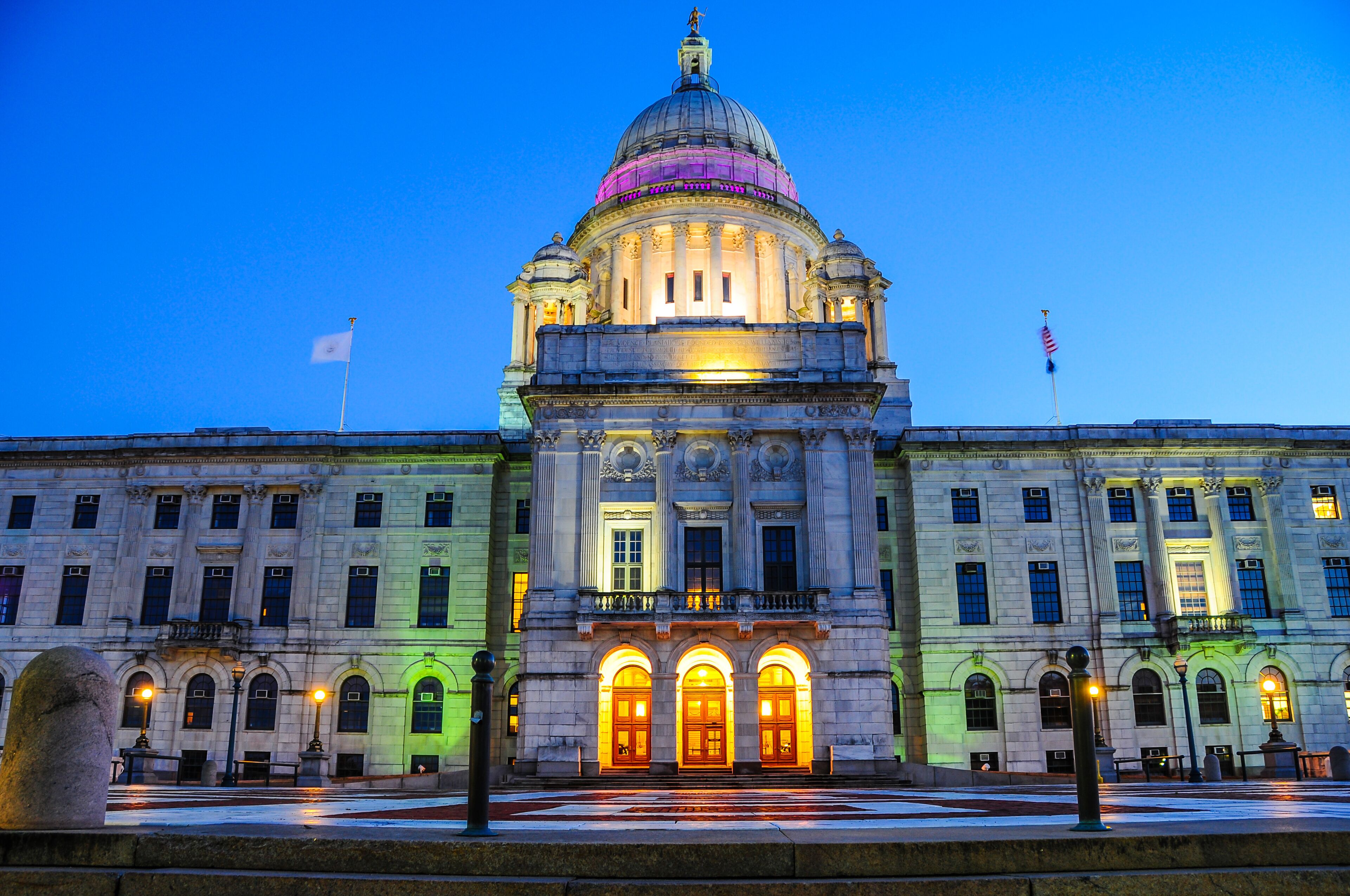 A grand building with a large dome and multiple flags, including the American flag.