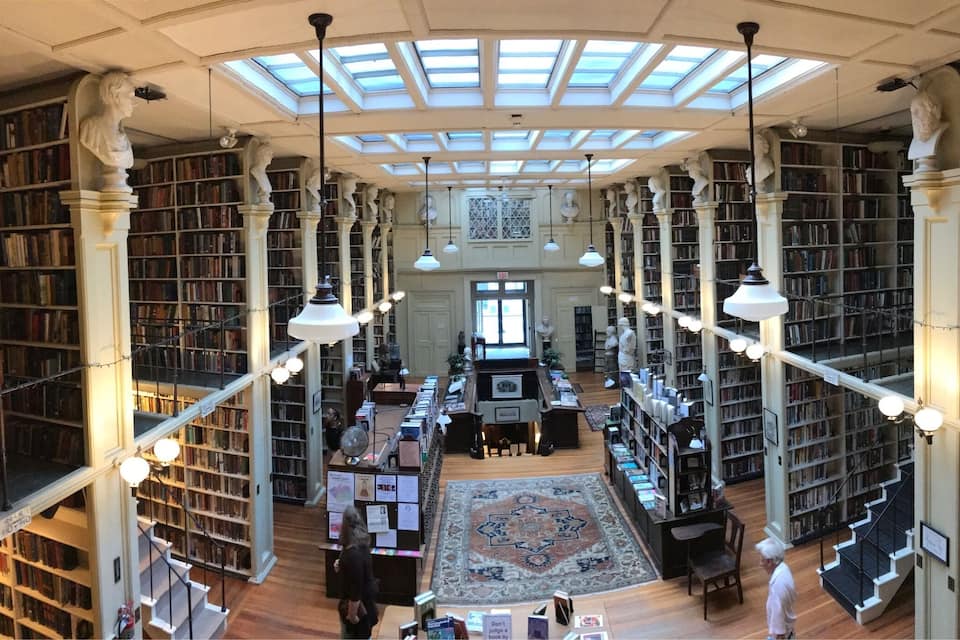 Una biblioteca àmplia i ben il·luminada amb alts sostres, ulls de bou i nombroses prestatgeries plenes de llibres.
