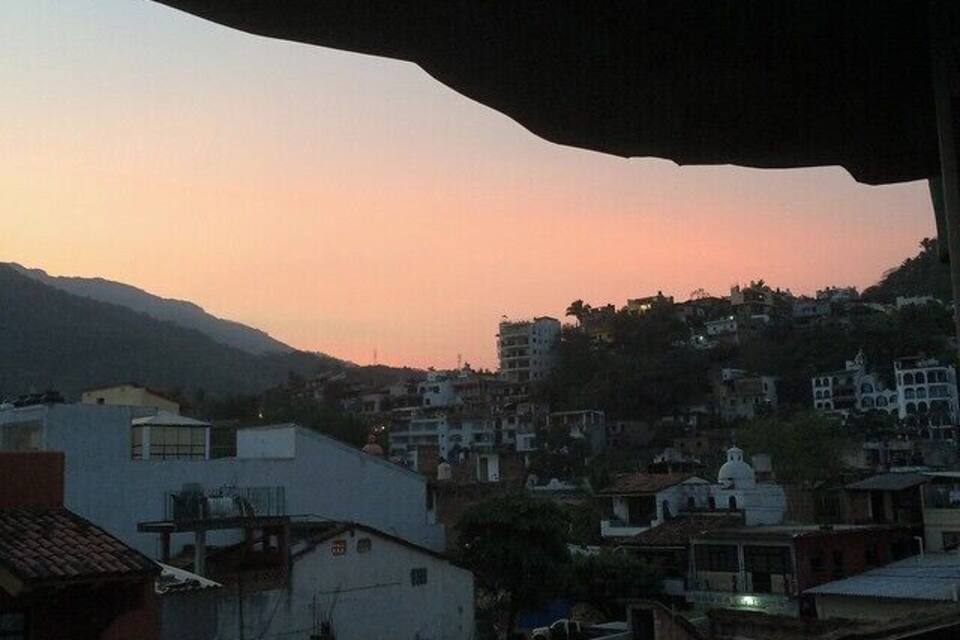 A sunset over a hilly town with buildings and a train track.