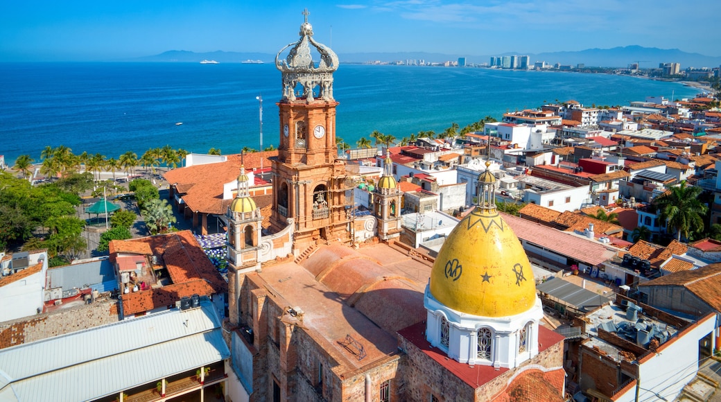 A coastal cityscape with a prominent church tower and a golden-domed building.