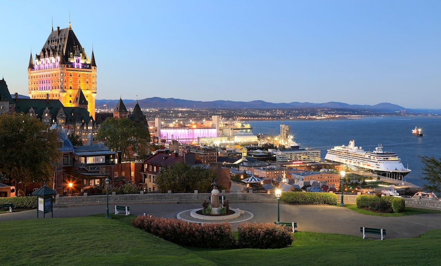 Une vue sur la ville, avec ses bâtiments historiques, un stade moderne et un navire de croisière amarré au bord de l’eau.