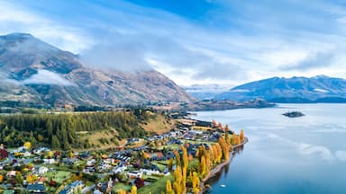 A mountainous landscape with a lake, a village, and autumn-colored trees.