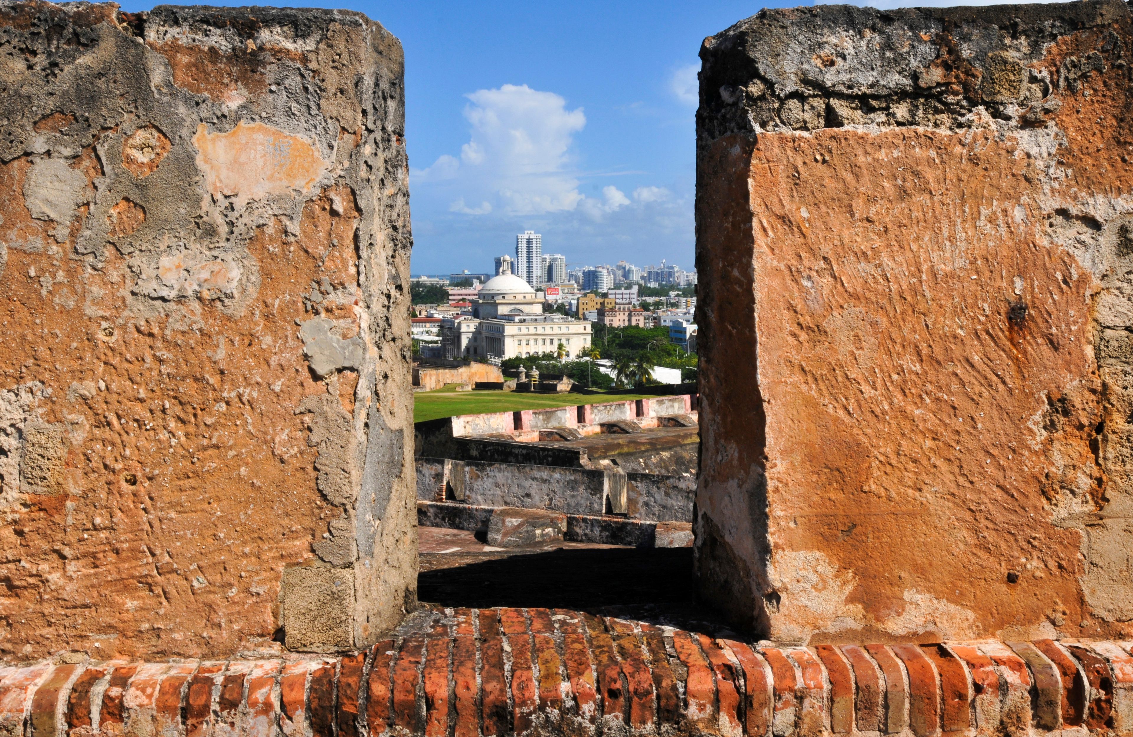 A view through ancient stone walls with a cityscape in the background.