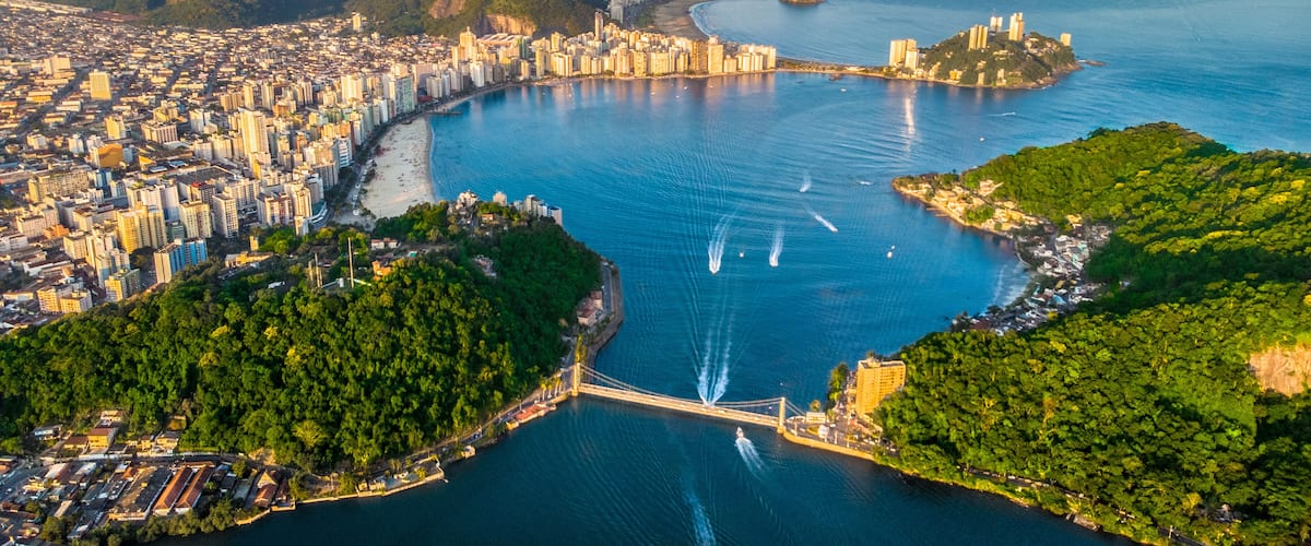 A coastal city with a bridge, dense urban area, and surrounding hills.