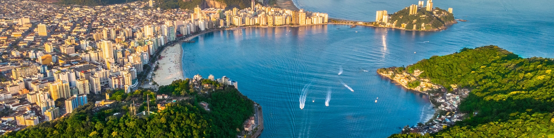 A coastal city with a bridge, dense urban area, and surrounding hills.