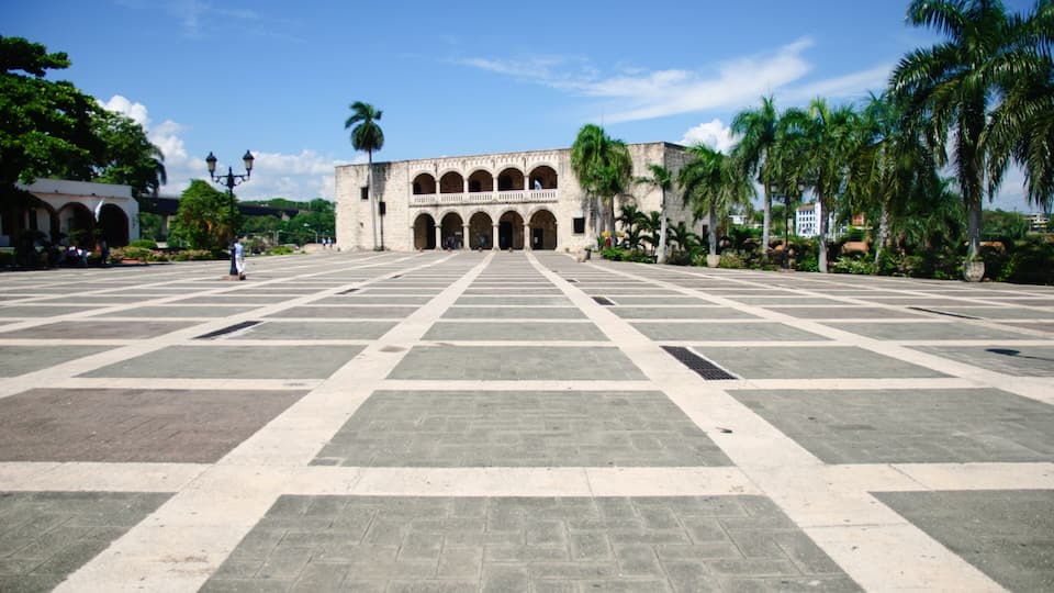 A large open plaza with a historic building featuring arches and a central courtyard.