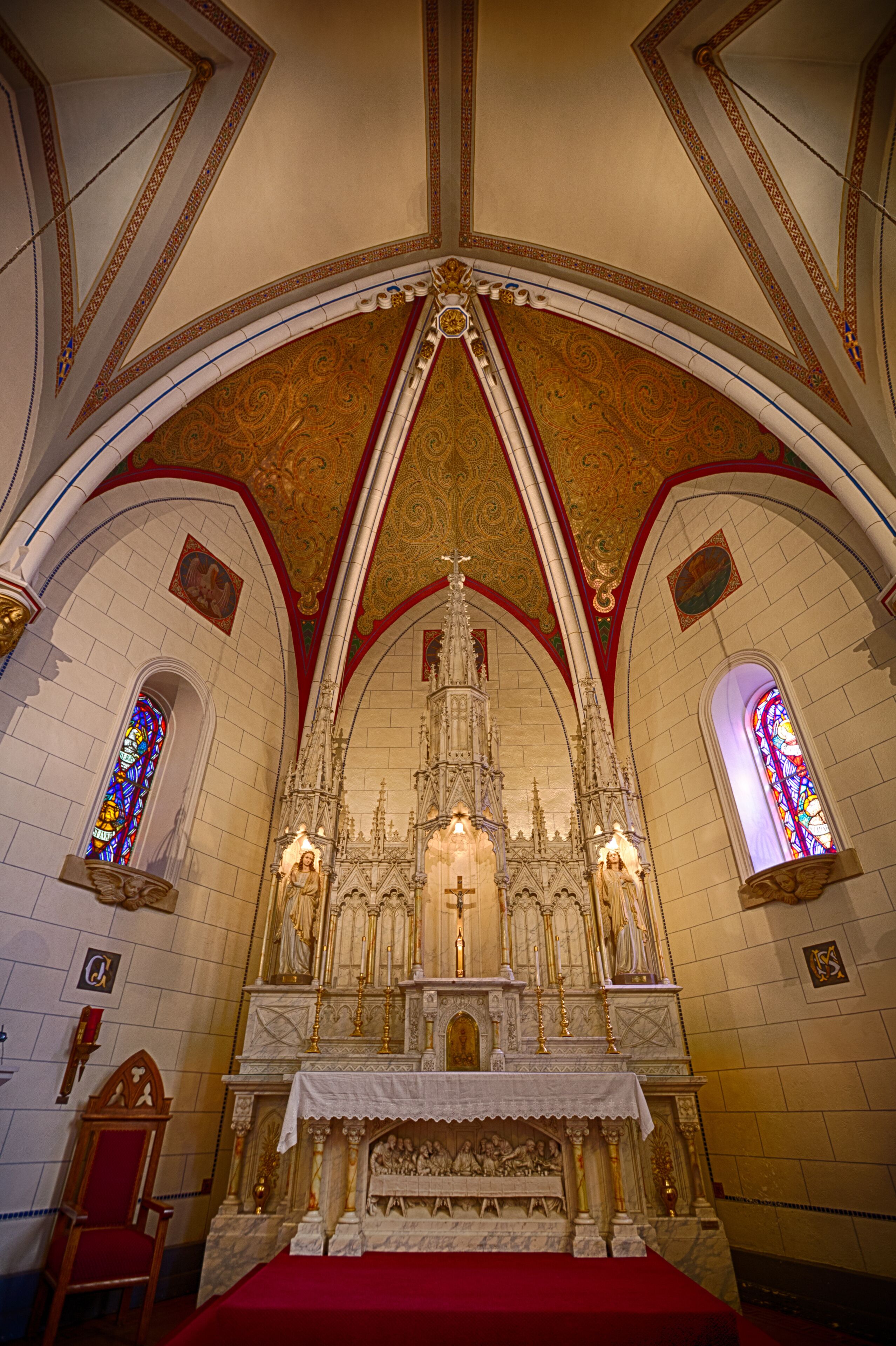 Interior de igreja ornamentado, com altar alto, vitrais e detalhada arte no teto.