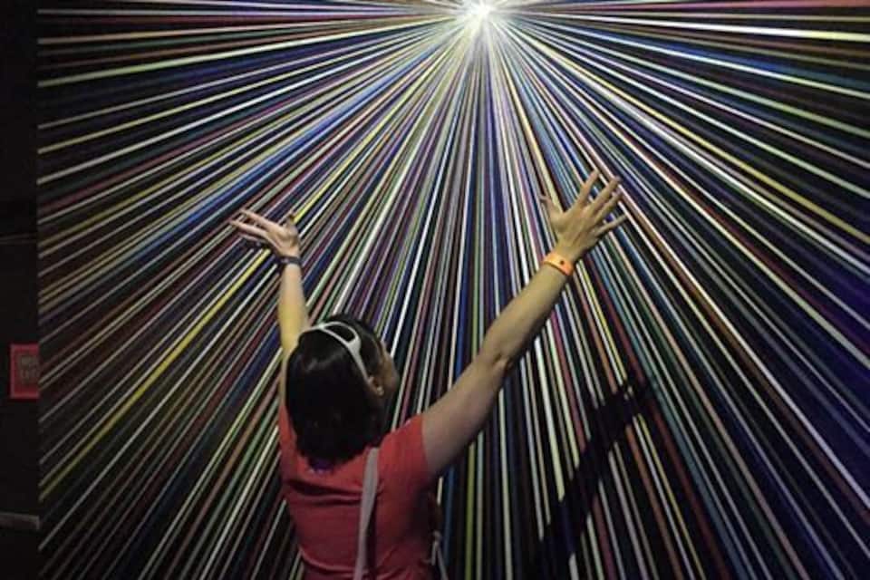 Una persona tende la mano verso una fonte di luce circondata da linee colorate.