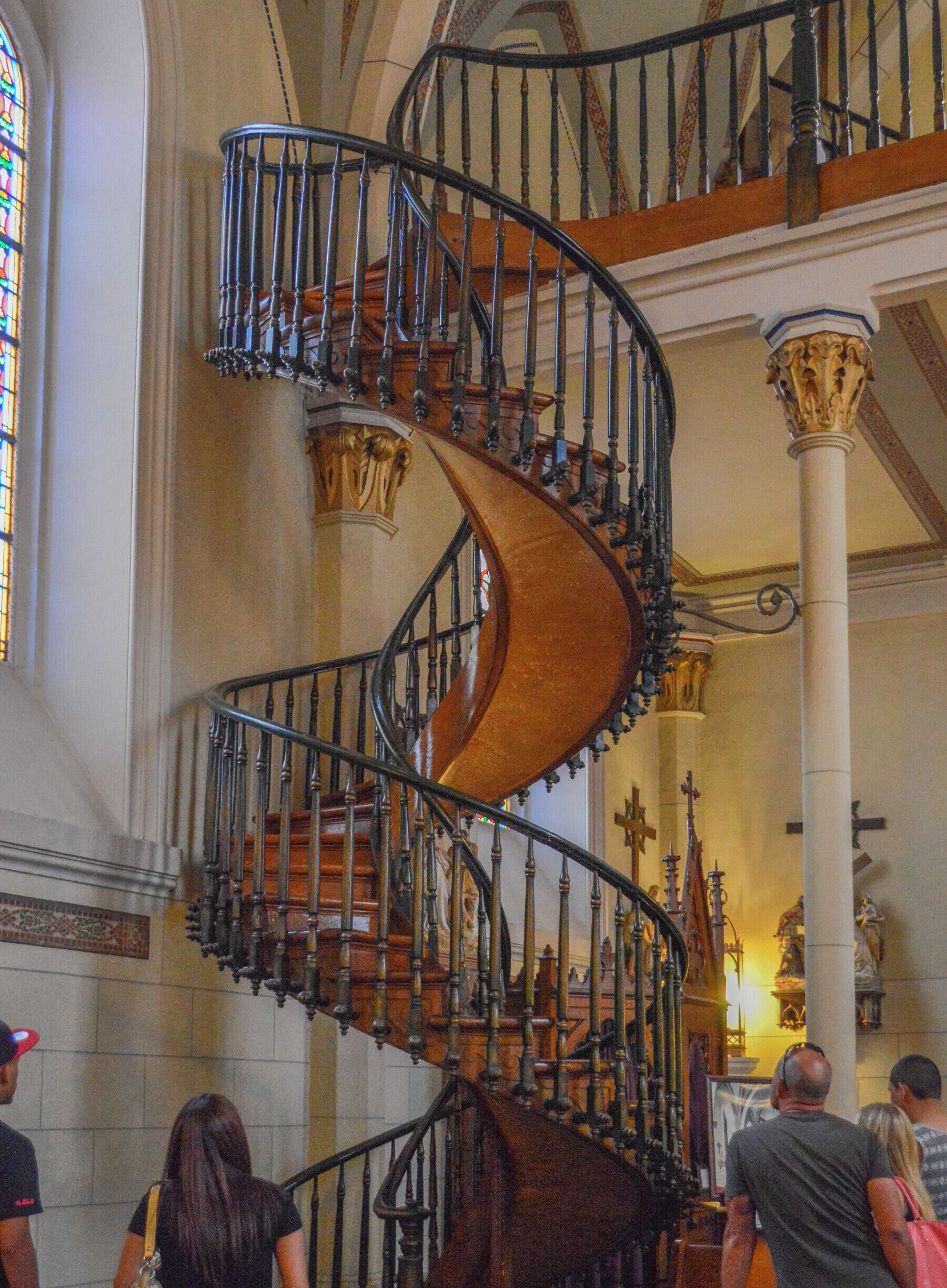 The famous and beautiful staircase in the Loretto Chapel in Santa Fe, NM. When the chapel was completed in 1878, there was no way to access the choir loft. It was suggested that a ladder be used, but the nuns who used the chapel didn't like this idea because of the long habits that they wore. So they prayed to St Joseph for a solution. Shorty thereafter a carpenter showed up and offered to build the staircase for them, but he needed total privacy to do so and locked himself in the chapel for 3 months. When he was done he left town, without even accepting payment. The staircase he built is not only beautiful, but it is an architectural wonder. It makes two complete 360 turns, there are not metal nails, and there is no center means of support.  The identity of the carpenter was never known. #newmexico #santafe #lorettochapel #church #stairs #architecture