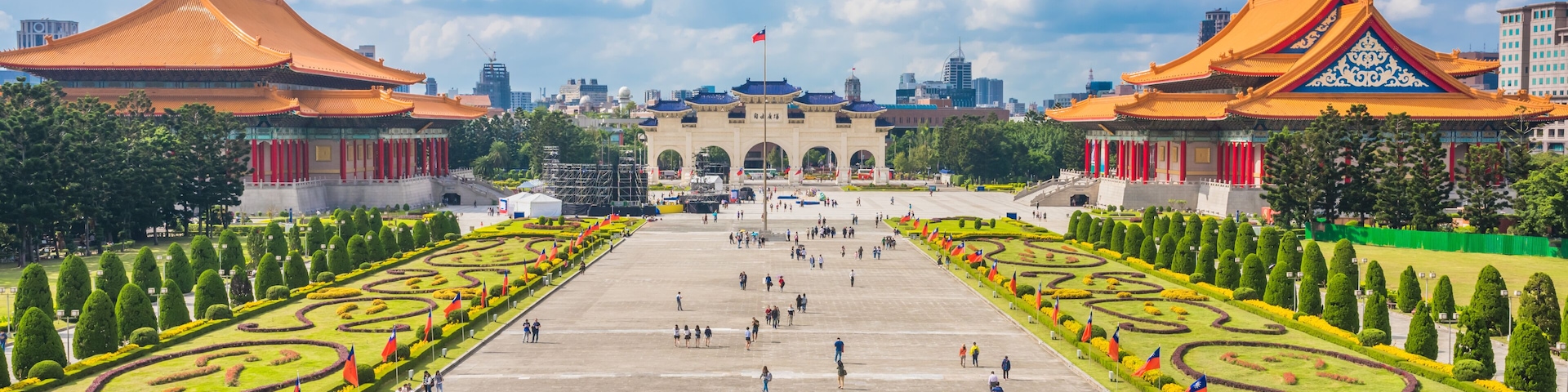 A large open plaza with traditional architecture, a central archway, and symmetrical gardens.