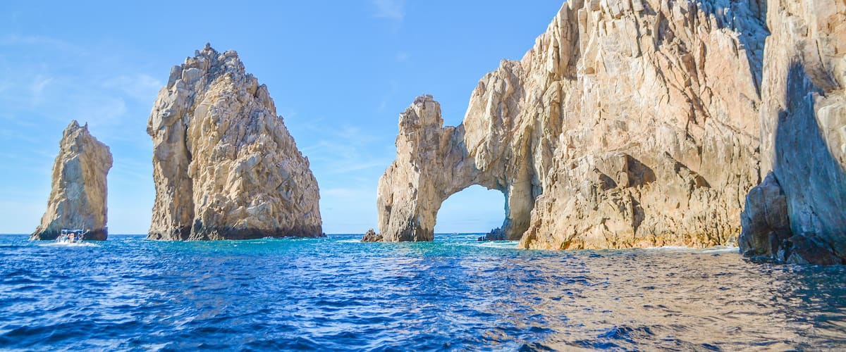 A coastal landscape with large rock formations and clear blue waters.