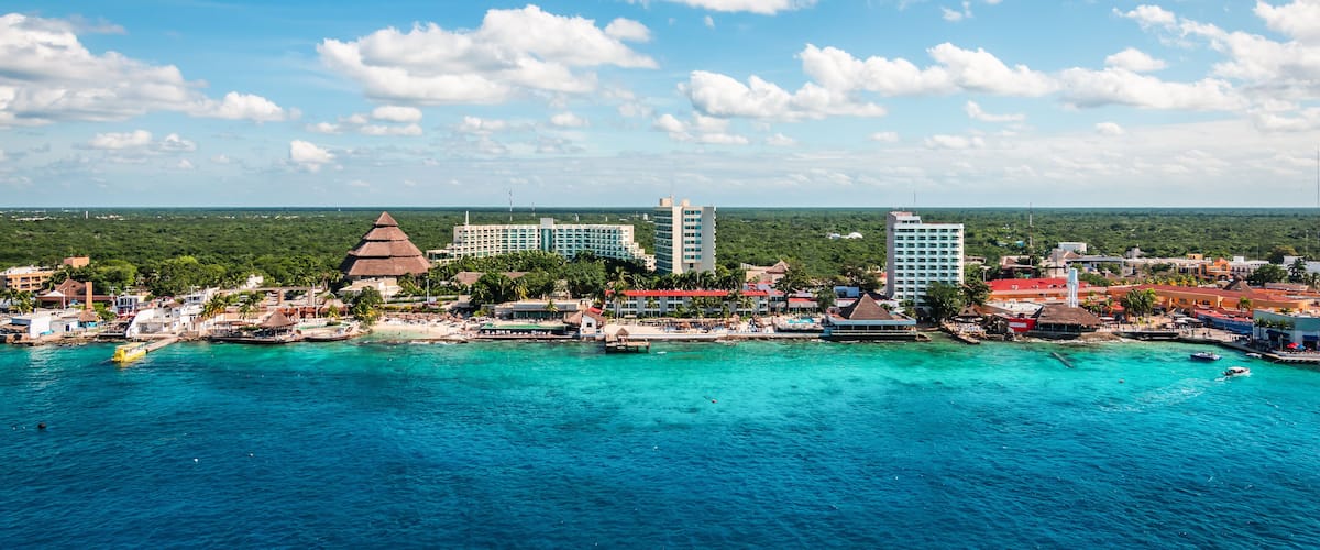 A coastal city with a clear blue sky, turquoise waters, and a mix of modern and traditional architecture.