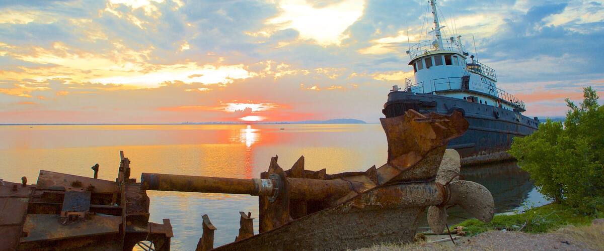 A large ship docked at a pier with a sunset in the background.